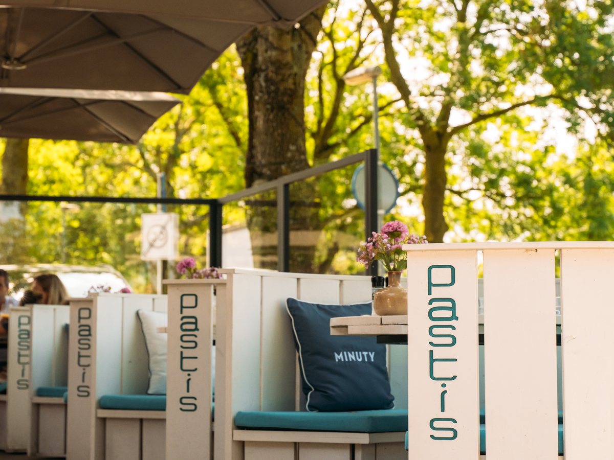 De comfortabele ronde banken van Brasserie Pastis op het terras, onder de vaste parasols