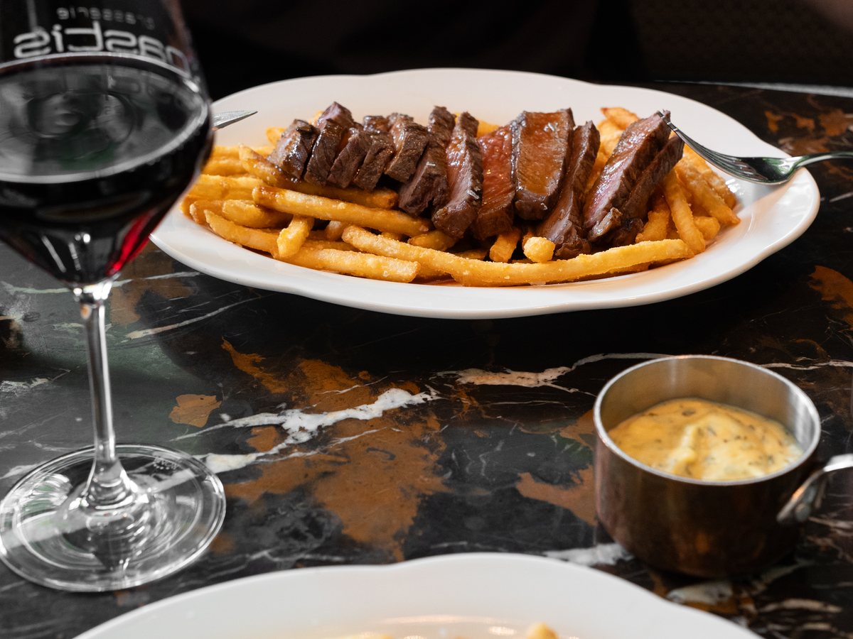 Steak met verse friet en een glas rode wijn op een marmeren tafel