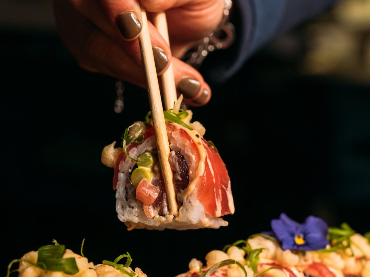 Sushi in een witte kom met stokjes ernaast